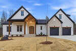 A modern farmhouse-style home in Youngsville at 3904 Cedar Knolls Drive, featuring white siding, stone accents, wood trim, two front-facing garage doors, a covered entry porch, and a freshly landscaped yard with sparse grass and young shrubs.