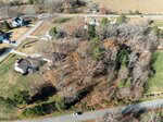 Aerial view of a Wake Forest suburban neighborhood with several houses, leafless trees, grass lawns, and main roads at the top and bottom. A white car is parked on the lower road near 1039 Heather Lane.