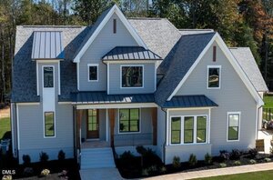 A two-story gray house with white trim at 3922 Cedar Knolls Drive, Youngsville, features multiple gabled roofs, large windows, a covered front porch with wooden pillars, and a landscaped yard, photographed on a sunny day.