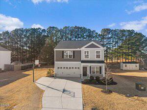Charming two-story suburban home at 55 Fall Harvest Court in Franklinton, featuring gray siding, a two-car garage, and a basketball hoop beside the driveway. Enjoy a spacious lawn with pine trees lining the backdrop.