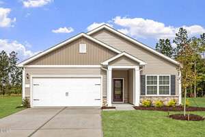 Charming single-story Oxford home at 109 Rhino Bend with beige siding, white trim, a double garage, and a cozy covered porch. Landscaped bushes and a young tree accent the front yard against a backdrop of grass and trees beneath a partly cloudy sky.