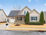 A two-story suburban house at 8 Hawthorne Lane, Youngsville, with light beige siding, stone accents, a gable roof, two tall evergreens out front, a leafless tree, white mailbox, and a driveway leading to a single-car garage.