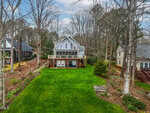 Situated at 651 Sagamore Drive in Louisburg, this two-story gray house with large windows and a wooden deck overlooks a spacious, well-maintained green lawn, surrounded by trees and neighboring homes on either side.