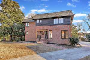 A brick house with a driveway and trees.