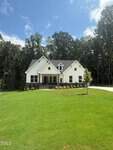 A modern two-story white house with dark roofing and a front porch sits on a large, neatly mowed lawn at 60 Valebrook Court in Youngsville, surrounded by trees under a blue sky with scattered clouds.