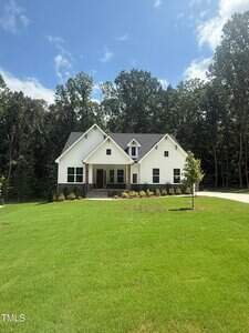 A modern two-story white house with dark roofing and a front porch sits on a large, neatly mowed lawn at 60 Valebrook Court in Youngsville, surrounded by trees under a blue sky with scattered clouds.