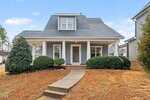 A gray, single-story house with white trim and a covered front porch at 201 Kipling Drive in Oxford, featuring a dormer window, walkway to the front door, bushes, and a patchy brown lawn.