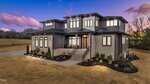 A modern two-story house at 30 Hartwood Lane in Youngsville features large windows, gray siding, and stone accents. The front steps lead to a covered entrance, with minimal landscaping on a spacious lot captured at dusk.