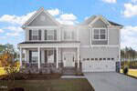 A two-story gray house with white trim at 105 Guardian Street, Youngsville. Features black shutters, a front porch, double garage, concrete driveway, and landscaped yard with trees and blue sky in the background.