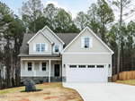 Two-story suburban house at 195 Purslane Drive in Franklinton with gray siding, white trim, a covered front porch, and a double garage. The wide driveway slopes upward, and the yard features patchy grass with tall pine trees in the background.