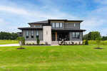 A modern two-story house at 130 Broadleaf Lane in Youngsville features dark gray siding, large windows, a stone accent wall, and a neatly landscaped front yard under a partly cloudy sky.