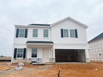 A newly constructed two-story white house with black shutters at 52 Plantation Drive, Youngsville. Features an attached two-car garage and a bare dirt front yard with construction materials stacked near the entrance and garage.