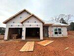 A single-story house under construction at 12 Bee Balm Court in Youngsville features exposed wood framing and house wrap. Two garage openings are visible, with construction materials scattered on the bare dirt yard. Trees and a cloudy sky are in the background.