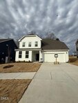 A two-story white house in Franklinton with a covered porch, attached garage, and a for sale sign on the front lawn at 50 Copperleaf Court. The sky is overcast with dramatic clouds, and the yard features brown grass and a young tree.