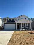 Two-story modern suburban house at 145 Sugar Pine Drive, Franklinton, with a dark blue and white exterior, attached double garage, small covered porch, landscaped front yard with young shrubs, and a freshly mown lawn under a clear blue sky.