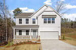 Charming two-story white house with gray roof at 150 Cordoba Drive, Franklinton. Features an attached two-car garage, covered front porch with columns, concrete driveway, grassy yard with young shrubs, plus trees and blue sky in the background.