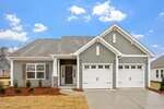 Charming single-story home at 136 Sugarmaple Way, Youngsville, with light gray siding, white trim, double garage doors, a small front porch, shuttered windows, and minimal landscaping on a new lawn under a partly cloudy sky.