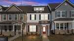 A two-story townhouse at 955 Alma Railway Drive, Wake Forest, features brick and siding exterior, white-framed windows, and a red front door. Captured at sunset with a purple sky, a small tree and walkway lead to the welcoming entrance.