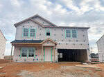 A two-story house at 48 Plantation Drive, Youngsville is under construction, wrapped in protective sheeting with exposed framing. The front door and windows are installed, but the garage is unfinished. The ground is bare dirt under a partly cloudy sky.