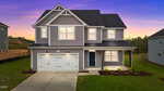 Charming two-story gray house with white trim at 30 Malbec Way, Youngsville. Features a double garage and covered porch, set against a vibrant sunset sky. Enjoy the well-maintained lawn and minimal landscaping out front.