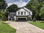 A modern two-story house at 17 Collins Street, Franklinton, with a black and white exterior, three-car garage, long curved driveway, and well-kept lawn, surrounded by trees under a partly cloudy sky.
