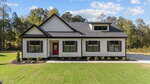 Modern single-story house at 35 Autumnwood Lane, Zebulon, with white siding, black trim and roof. Features large windows, a bright red front door, a covered porch, and a neatly landscaped front yard with green grass.