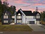 Modern two-story house at 219 Forest Bridge Road, Youngsville, featuring a black and white exterior, large windows, an attached three-car garage, and a spacious driveway, set against trees and a pink sunset sky.