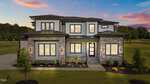 Modern two-story house at 200 Broadleaf Lane, Youngsville, with large windows, stone and siding exterior illuminated at sunset; neatly landscaped front yard features small shrubs and a green lawn.