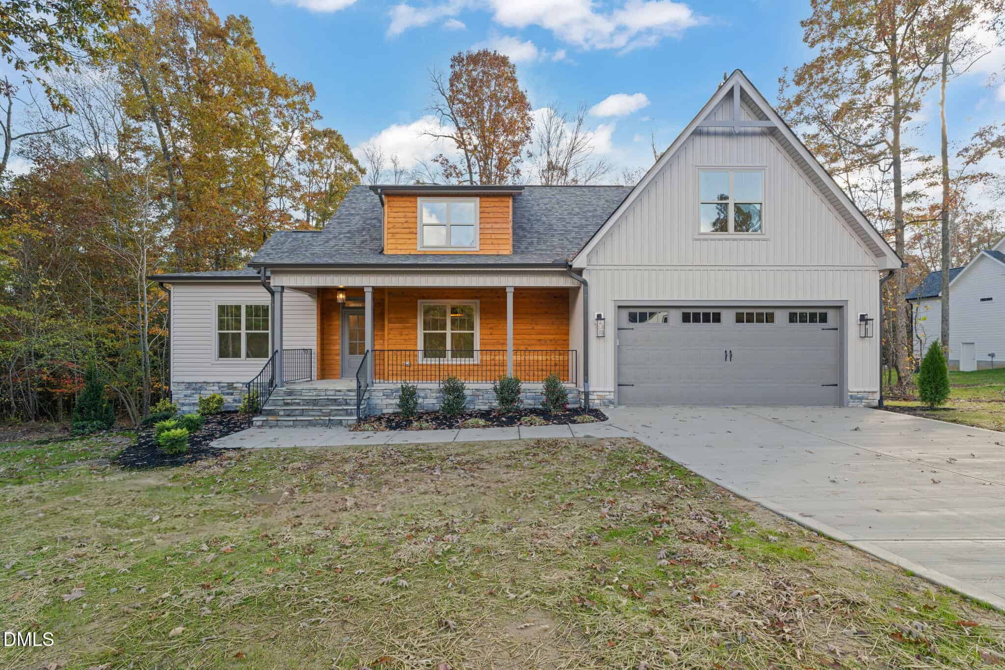 A modern two-story house at 85 Beauview Way in Zebulon, featuring gray siding, wooden accents, a covered front porch, double garage doors, and a concrete driveway, all set among trees with a partially grassed yard.