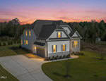 A modern two-story house with white siding and gray roof is lit warmly at dusk. Nestled at 55 Harvest View Way in Franklinton, the home sits on a large, manicured lawn surrounded by trees under a colorful sunset sky.