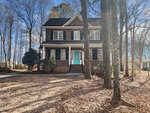 Charming two-story brick house in Franklinton with black shutters, a covered front porch, and a turquoise front door at 4445 W River Road, surrounded by tall trees and a leaf-covered yard on a sunny day.