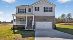 Charming two-story suburban house at 145 Babbling Creek Drive, Youngsville, with brick and siding exterior, covered front porch, white railing, and double garage. Enjoy a spacious lawn, driveway, landscaping, blue sky, and trees in the background.