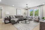 A modern living room at 35 Copperleaf Court in Franklinton features a gray sectional sofa, patterned pillows, accent chairs, round coffee tables, a rug, and large windows. Decor includes lamps, plants, and stylish wall art.