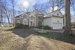 A two-story suburban house at 105 Richland Drive, Youngsville, with brick and white siding, large windows, an arched entryway, and a yard featuring a birdbath. Surrounded by trees, it also offers an attached two-car garage on the right.