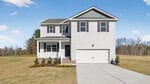 A two-story modern suburban house at 120 Babbling Creek Drive in Youngsville features white siding, a front porch, attached two-car garage, and a large, well-kept lawn under a clear blue sky.