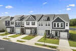 A row of modern, two-story townhouses with garages lines 227 Alberta Drive in Franklinton, featuring neatly landscaped lawns and a paved street under a clear blue sky.