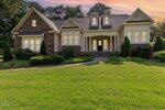 A single-story suburban house at 1096 Silverleaf Drive, Youngsville, with stone and beige siding, large front windows, a covered porch with columns, and well-kept landscaping, pictured at sunset beneath a glowing sky.