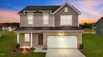 A two-story suburban house with gray siding and brick facade, white trim, double garage, and a neatly landscaped front yard, set against a colorful sunset sky.