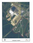 Aerial map showing an industrial area with buildings, parking lots, and cleared land. A large plot of undeveloped land is outlined in red on the right side, intersected by dirt paths, with roads and forested areas surrounding the site.