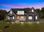 A modern, dark gray house with white trim and wooden accents sits on a large, well-kept lawn under a vibrant blue and purple sunset sky, surrounded by trees.
