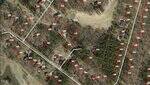 Aerial view of a residential neighborhood map with property boundary lines, house numbers, and red dots marking house locations. There are roads, wooded areas, and a golf course visible.