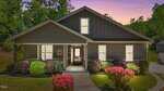 A modern single-story house with dark gray siding, white trim, a covered front porch, and large front windows, surrounded by neatly trimmed bushes and pink flowering shrubs at sunset.