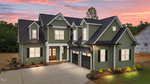 A two-story green house with white trim and black shutters, featuring double front doors and a two-car garage, is illuminated at sunset with a wooded background and a neighboring house under construction.