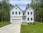 A large white modern two-story house with a double garage, multiple front-facing windows, and a well-kept lawn, surrounded by tall trees and greenery under a mostly clear sky.