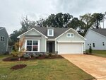 A newly built, light gray single-family home with white trim and a two-car garage. A "SOLD" sign is in the window, and there is fresh landscaping and grass in the front yard. The sky is overcast.