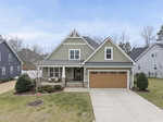 A modern two-story house with green siding on 55 Walking Trail in Youngsville, featuring a brown garage door, covered front porch, well-kept lawn, and nestled between neighboring homes on a suburban street.