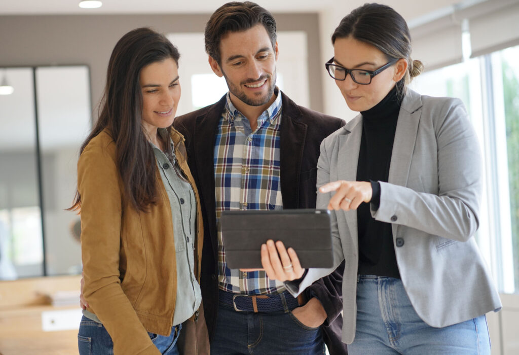 Couple viewing an iPad screen with their Real Estate Broker while touring a home for sale.