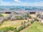 Aerial view of two adjoining wooded and grassy land plots outlined in white, labeled 6150 Bob Daniel Rd and 6142 Bob Daniel Rd, with trees, fields, and a road visible nearby.