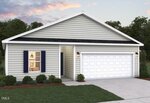A single-story house with light gray horizontal siding, a dark shingled roof, white trim, and a double garage door. There are two exterior lights, one window with dark shutters, and shrubs near the entrance.