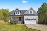 A two-story suburban house at 175 Sorrel Drive in Franklinton features gray siding, white trim, a covered front porch, and a double garage. The lawn is green and well-kept, with a concrete driveway leading up to the home. Mature trees surround the property in the background.